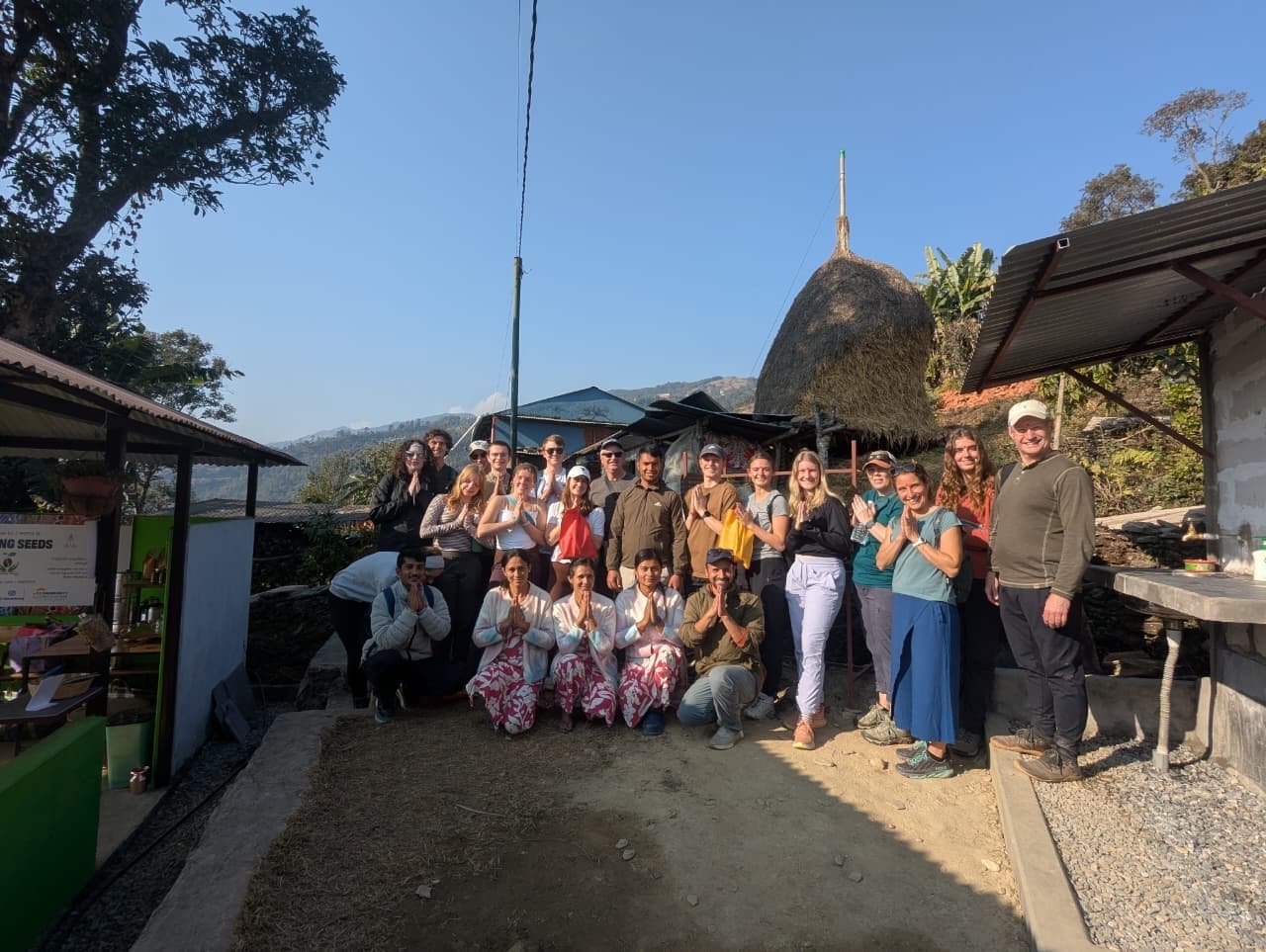 Luther College students with their hosts at a coffee farm in Sarangkot, hands together in namaste